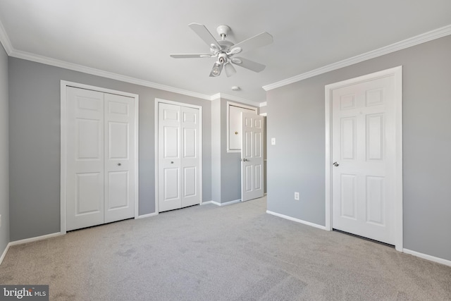 unfurnished bedroom featuring ceiling fan, two closets, ornamental molding, and light carpet