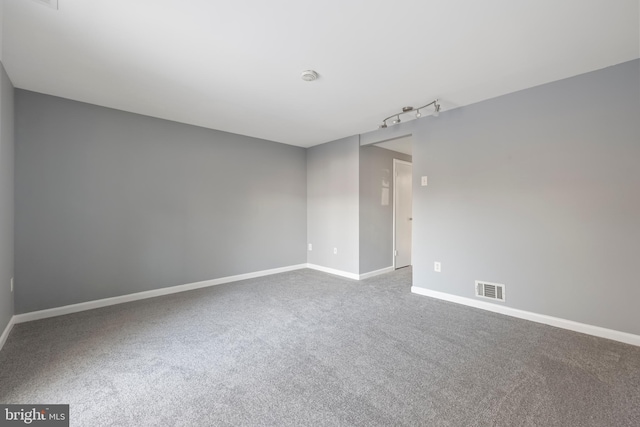 carpeted empty room featuring rail lighting