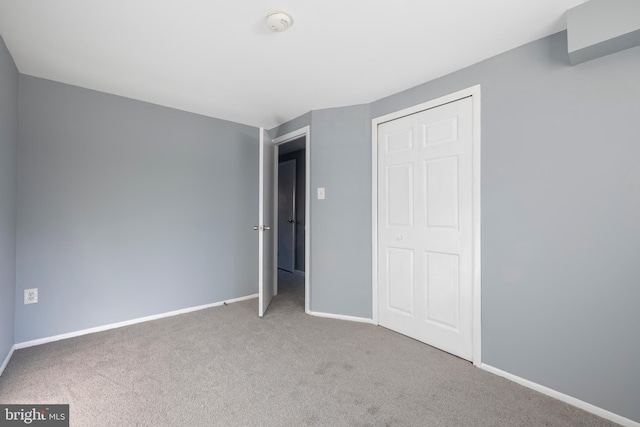 unfurnished bedroom with a closet and light carpet