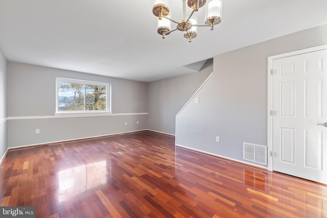 unfurnished room featuring an inviting chandelier and dark hardwood / wood-style floors