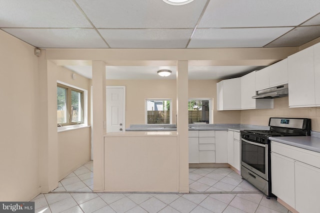 kitchen featuring light tile patterned floors, stainless steel range with gas cooktop, white cabinets, and tasteful backsplash