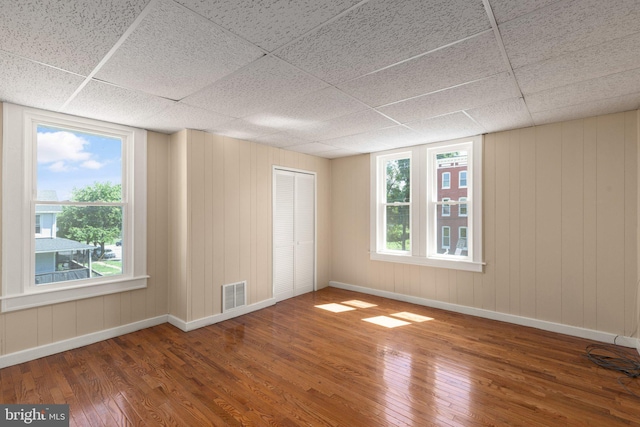 spare room featuring hardwood / wood-style flooring and a drop ceiling