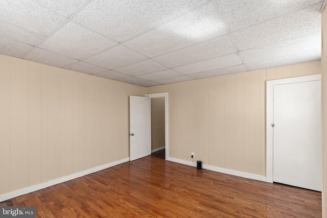 empty room featuring dark hardwood / wood-style flooring and a drop ceiling