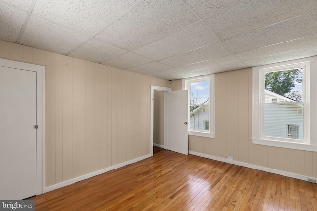 spare room with hardwood / wood-style floors, plenty of natural light, and a drop ceiling