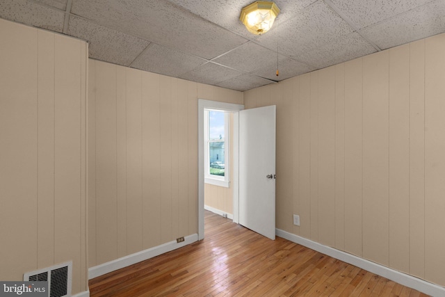 empty room with hardwood / wood-style flooring and a paneled ceiling