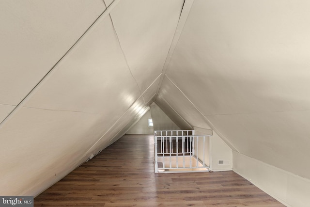 additional living space with wood-type flooring and vaulted ceiling