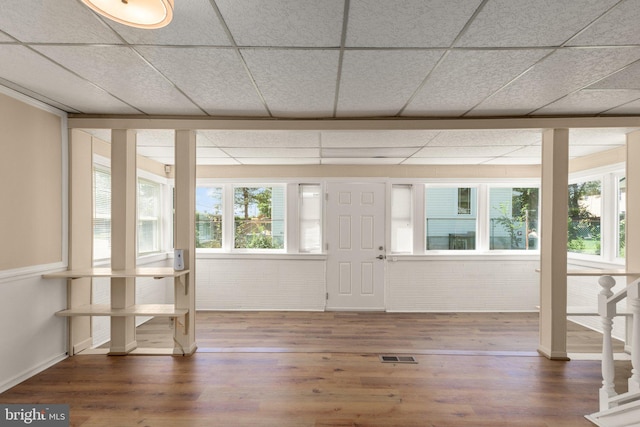 interior space featuring brick wall, dark hardwood / wood-style flooring, and a paneled ceiling