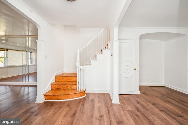 stairway with hardwood / wood-style flooring and crown molding