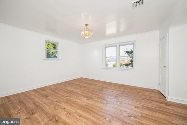 spare room with crown molding, a notable chandelier, and light hardwood / wood-style floors