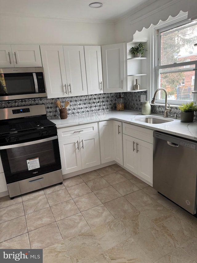 kitchen featuring backsplash, appliances with stainless steel finishes, sink, and white cabinets