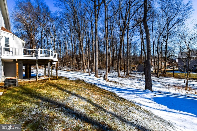 yard covered in snow with a wooden deck and central air condition unit