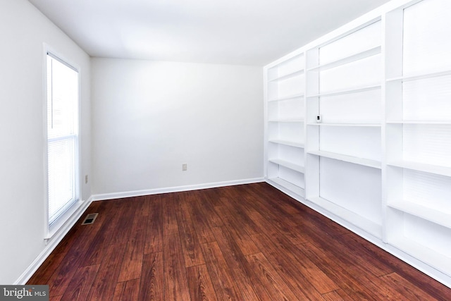 empty room featuring a healthy amount of sunlight and dark hardwood / wood-style flooring