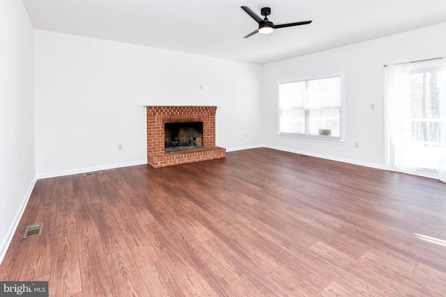 unfurnished living room with a brick fireplace, hardwood / wood-style floors, and ceiling fan