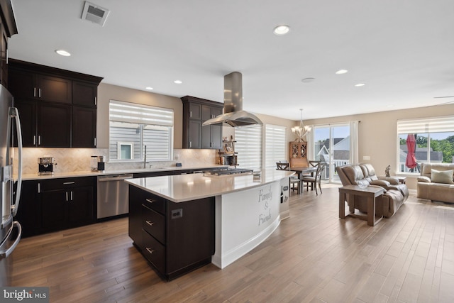 kitchen featuring appliances with stainless steel finishes, sink, hanging light fixtures, island exhaust hood, and a center island