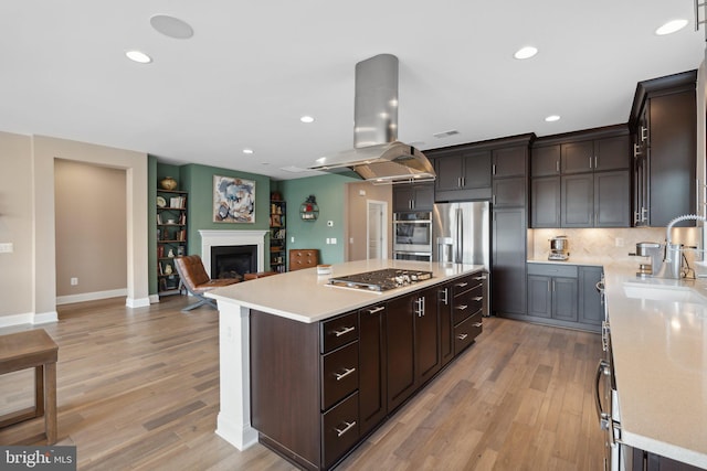 kitchen with sink, island range hood, a center island, and appliances with stainless steel finishes