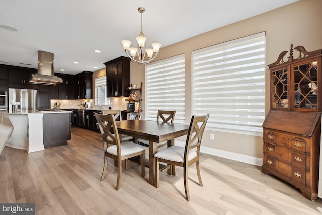 dining space featuring sink, a notable chandelier, and light hardwood / wood-style floors