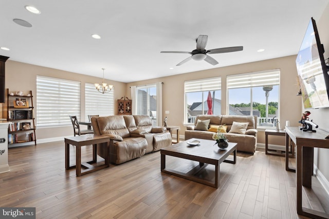 living room featuring ceiling fan with notable chandelier and hardwood / wood-style floors