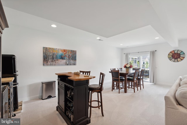 dining space with beam ceiling and light carpet