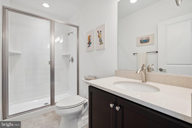 bathroom with a shower with door, vanity, tile patterned floors, and toilet