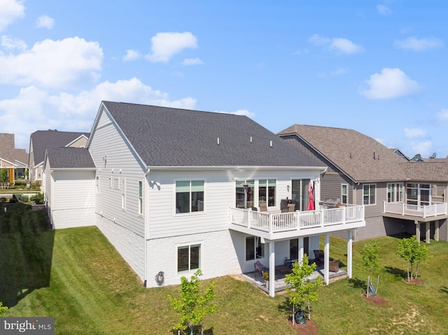 rear view of house featuring a wooden deck, a yard, and a patio area