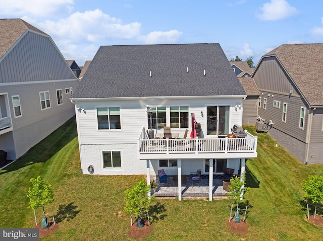 back of property featuring a balcony, a patio area, and a lawn