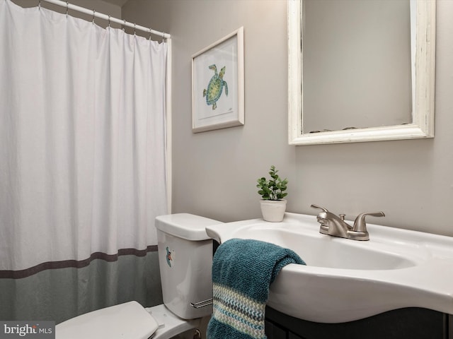 bathroom with toilet, a sink, and a shower with shower curtain