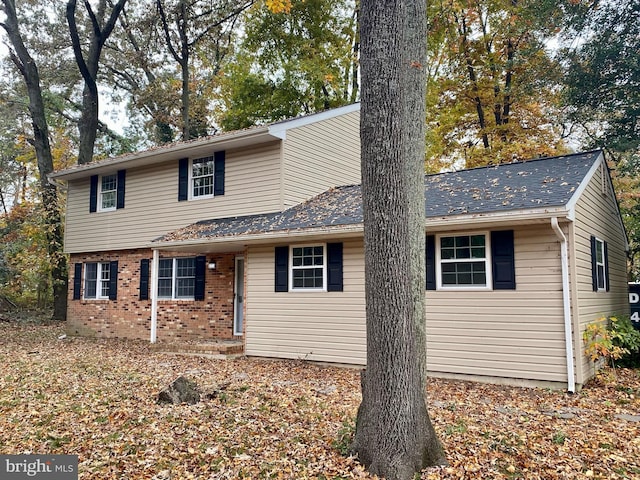 traditional-style home featuring brick siding and a shingled roof