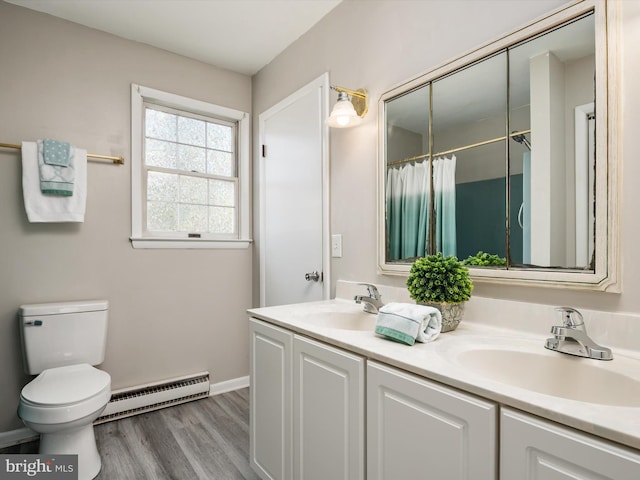 full bath featuring toilet, double vanity, baseboard heating, and a sink