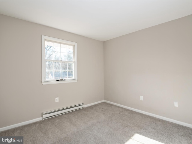 spare room with a baseboard heating unit, carpet flooring, and baseboards