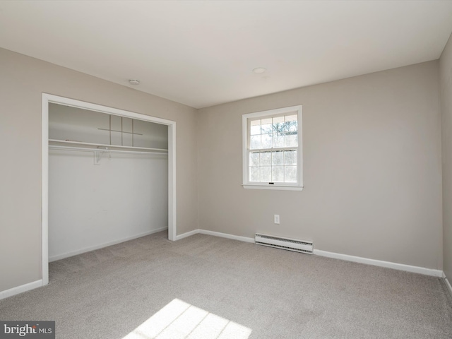 unfurnished bedroom with carpet floors, baseboard heating, a closet, and baseboards