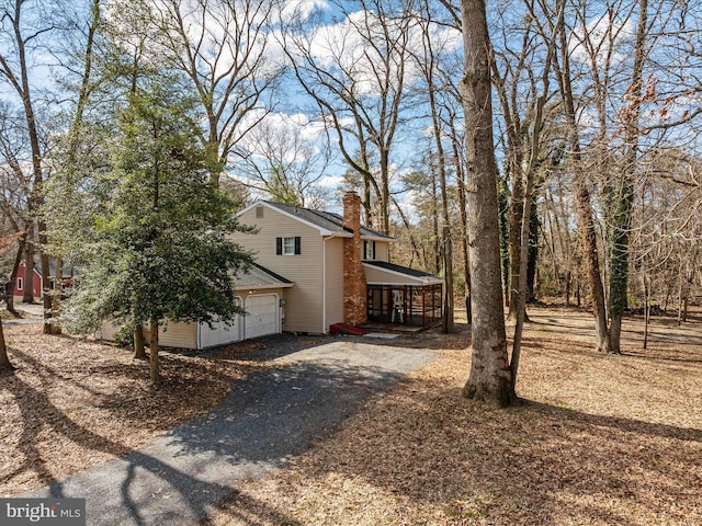 view of side of property featuring driveway, a porch, and a chimney