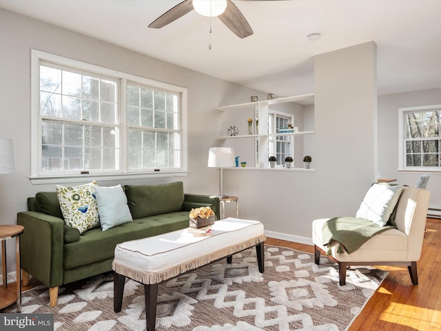 living area featuring ceiling fan, baseboards, and wood finished floors