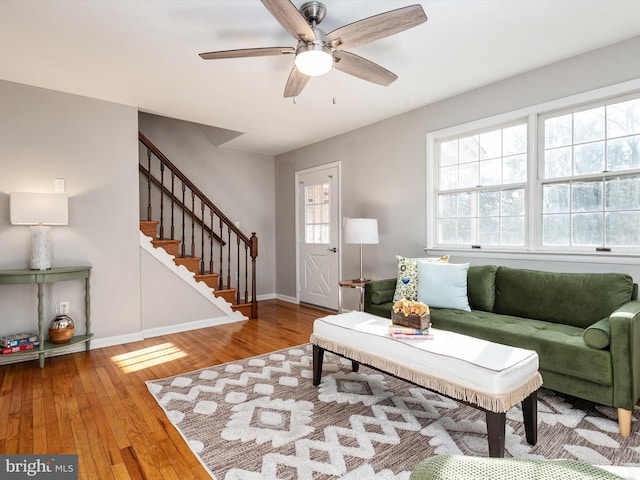 living area featuring baseboards, a healthy amount of sunlight, stairway, and hardwood / wood-style floors