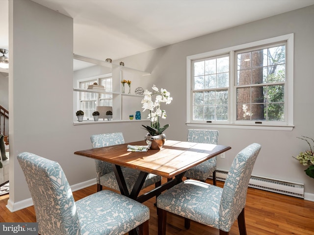 dining space with a baseboard radiator, baseboards, and wood finished floors