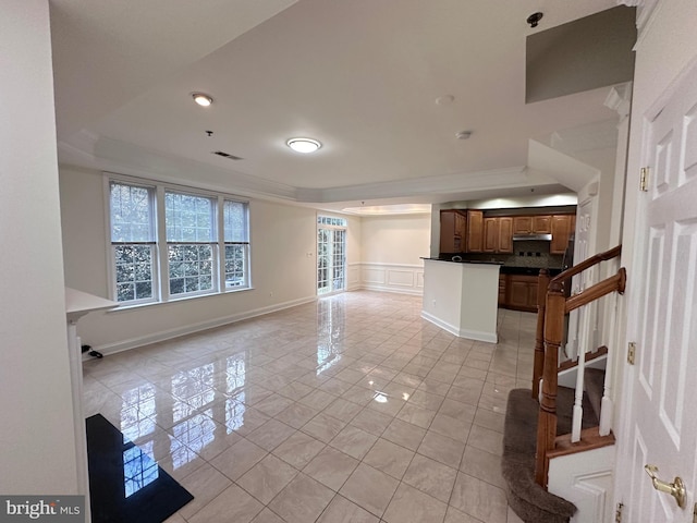 unfurnished living room featuring crown molding, a raised ceiling, and light tile patterned flooring