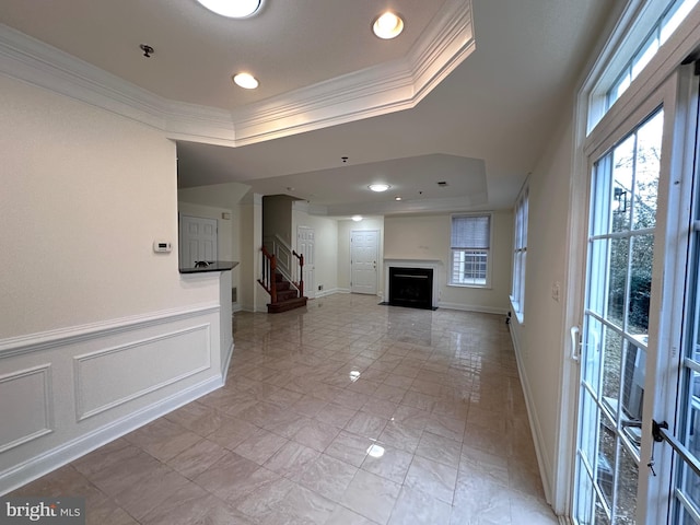 unfurnished living room featuring ornamental molding and a tray ceiling