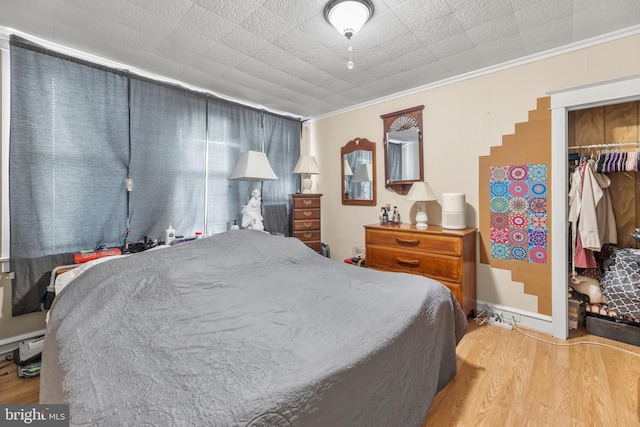 bedroom with crown molding, a walk in closet, wood-type flooring, and a closet