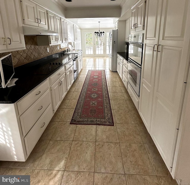 kitchen featuring tasteful backsplash, white cabinetry, sink, stainless steel appliances, and light tile patterned flooring