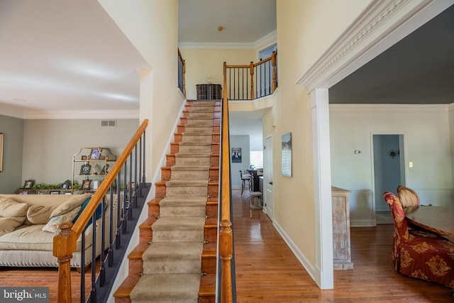 staircase with hardwood / wood-style flooring and crown molding