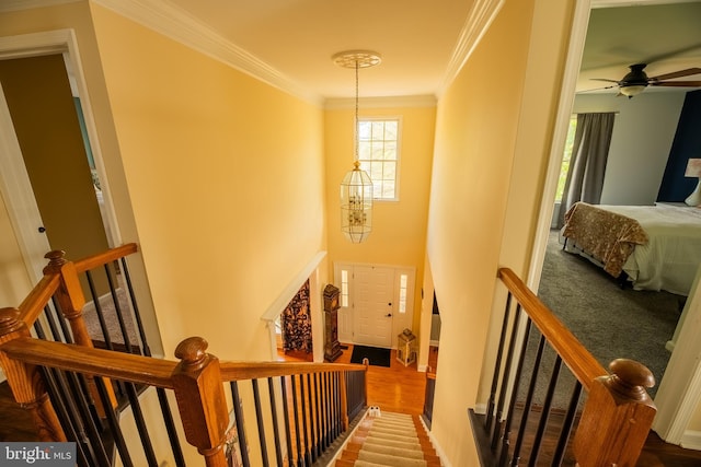 staircase with crown molding, wood-type flooring, and a chandelier