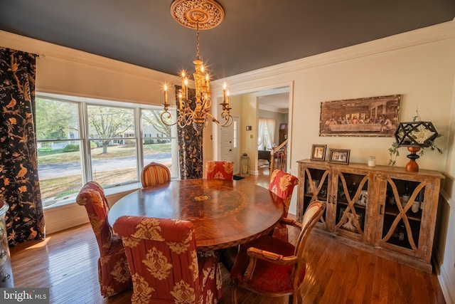 dining area with hardwood / wood-style floors, a notable chandelier, and ornamental molding