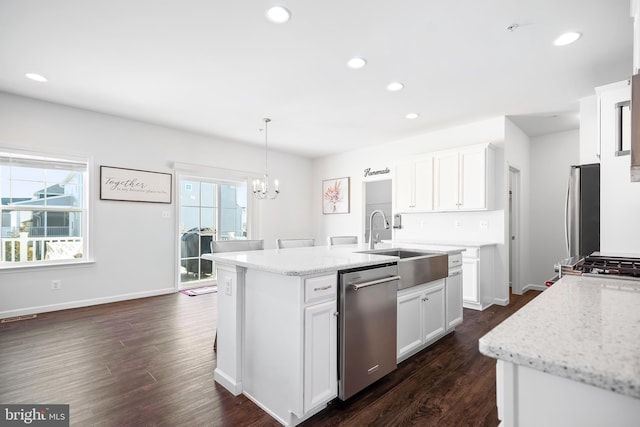 kitchen featuring appliances with stainless steel finishes, decorative light fixtures, a kitchen island with sink, and white cabinets