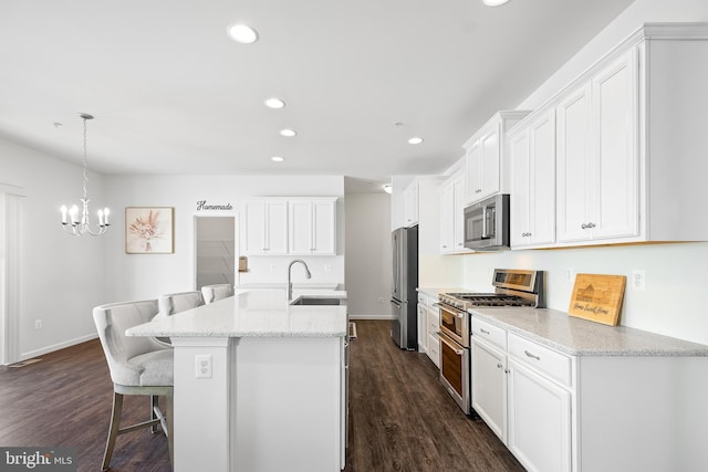 kitchen featuring white cabinetry, an island with sink, sink, appliances with stainless steel finishes, and pendant lighting