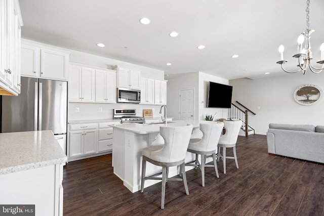 kitchen featuring white cabinetry, appliances with stainless steel finishes, a kitchen island with sink, and dark hardwood / wood-style flooring