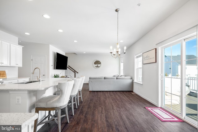 kitchen with dark wood-type flooring, pendant lighting, a breakfast bar, sink, and white cabinetry