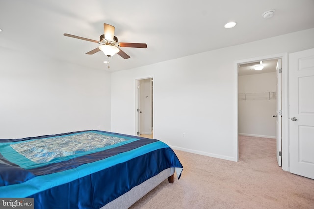 carpeted bedroom with a spacious closet, ceiling fan, and a closet