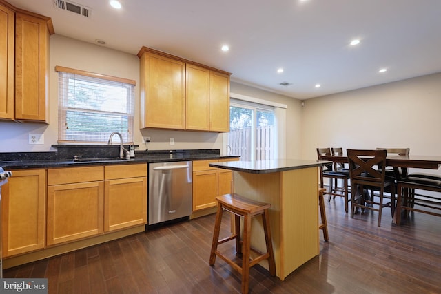 kitchen with a breakfast bar, dishwasher, sink, a center island, and dark wood-type flooring