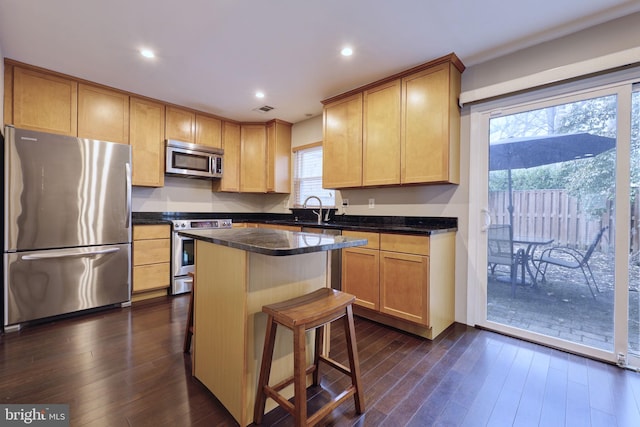 kitchen featuring a breakfast bar, sink, dark hardwood / wood-style floors, a kitchen island, and stainless steel appliances