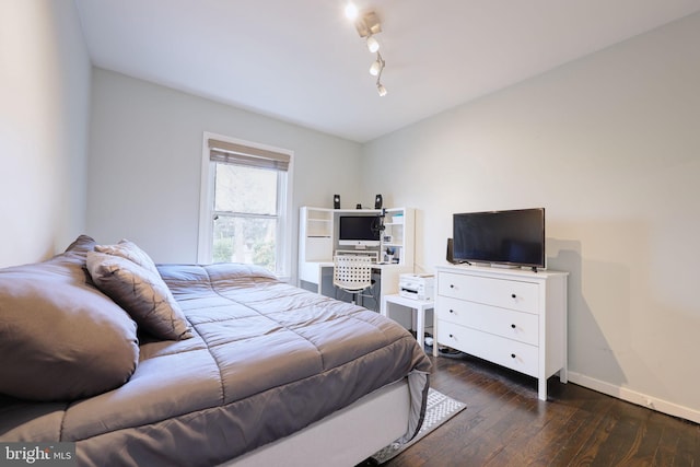 bedroom with dark hardwood / wood-style flooring and rail lighting