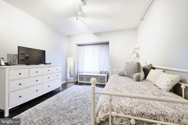 bedroom with dark hardwood / wood-style flooring and rail lighting